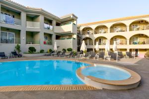 a pool in front of a hotel with chairs and umbrellas at White Olive Premium Laganas in Laganas