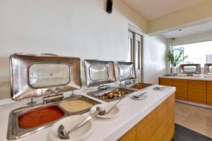 a kitchen with two sinks and two trays of food at White Olive Premium Laganas in Laganas