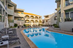 a hotel pool with chairs and umbrellas in a courtyard at White Olive Premium Laganas in Laganas