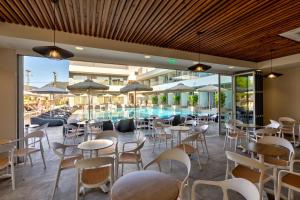 a restaurant with tables and chairs and a swimming pool at White Olive Premium Laganas in Laganas