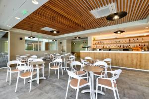 a restaurant with white chairs and tables and a bar at White Olive Premium Laganas in Laganas