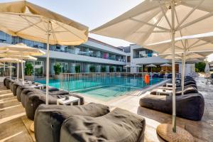 a swimming pool with chairs and umbrellas in front of a building at White Olive Premium Laganas in Laganas