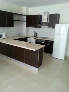 uma cozinha com armários castanhos e um frigorífico branco em Potamos Apartment em Limassol