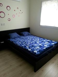 sypialnia z łóżkiem z niebieską kołdrą i oknem w obiekcie Potamos Apartment w mieście Limassol