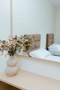 a vase with flowers on a table in front of a mirror at Urban Escape Guesthouse in Shkodër +12 photos