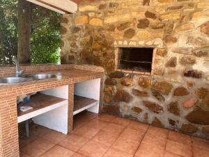 a stone kitchen with a sink and a stone fireplace at Villa Natalia in La Zarzuela