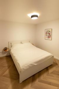 a white bed in a room with a wooden floor at 6 persons Luxury Appartement in Citycentre Breda in Breda