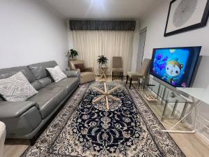 Una sala de estar con un sofá y un televisor de pantalla plana. en ADELAIDE CBD APARTMENT - 3BR, 2BATH & CARPARK, en Adelaida