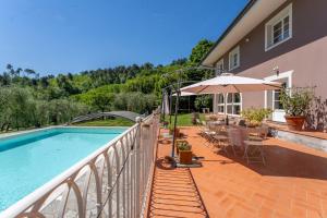 un balcon avec une piscine et un parasol dans l'établissement Villa Oliviana, à Montecarlo