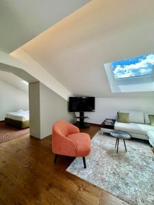 sala de estar con silla naranja y sofá en Romantico Attico Cuneo, en Cuneo