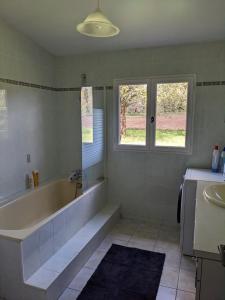 a bathroom with a large tub and two windows at Maison au calme en Dordogne in Trémolat