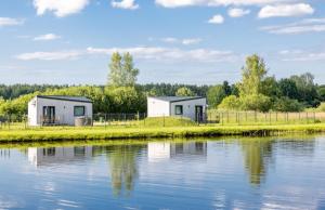 DzilnasKukuzes的水体岸边的两座房子