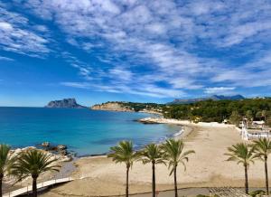 een strand met palmbomen en de oceaan bij CASA CHOULOU Moraira in Moraira