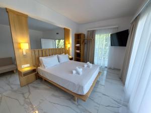 a bedroom with a large white bed and a television at Blue Bay Hotel in Iraklitsa