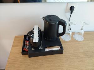 a black coffee maker on a table with wine glasses at Blue Bay Hotel in Iraklitsa