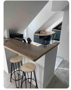 une cuisine avec un comptoir et deux tabourets au bar dans l'établissement bel appartement 4 personnes, à Port-en-Bessin-Huppain