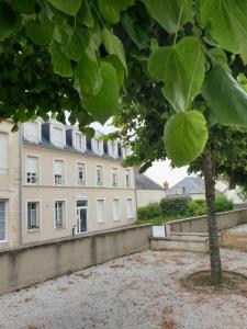 un arbre devant un grand bâtiment dans l'établissement bel appartement 4 personnes, à Port-en-Bessin-Huppain