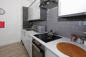 a kitchen with a stove and a microwave at Sapphire House Apartments in Telford