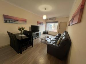 Una sala de estar con un sofá de cuero negro y una mesa. en Beach side holiday unit, en Port Adelaide