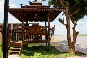 a gazebo with a bench and a tree at Mekong Tarawadee Villa in Tha Bo