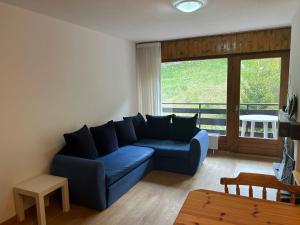 a living room with a blue couch in front of a window at Ramuge COSY & MOUNTAINS apartments in Veysonnaz