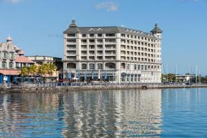 Un gran edificio blanco al lado de un cuerpo de agua. en Labourdonnais Waterfront Hotel, en Port Louis