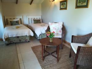 a room with two beds and a table and a chair at Avoca River Cabins in Addo