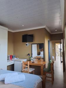 a bedroom with a bed and a table and a kitchen at Fountain Beach House-Elabahambi in Kiddʼs Beach