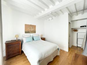 a white bedroom with a bed and a dresser at Le 58 Bayeux bel apt bien équipé centre ville parking gratuit à proximité in Bayeux