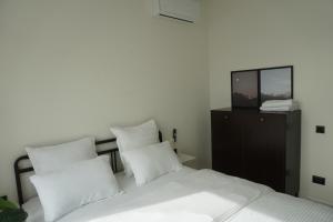 a bedroom with a bed with white pillows and a television at Домик 2 Kok Tobe Village in Almaty