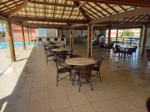 a patio with tables and chairs and a pool at Pérola Rosa 04 in Ilhéus