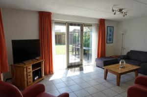 a living room with a couch and a tv at Kustverhuur, Park Scheldeveste Zwin 015, met grote omheinde tuin in Breskens