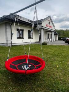 a red swing in the grass in front of a store at Dworek Kolorado dom 180 m2 na wyłączność - wyposażony in Klimki