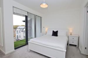 a white bedroom with a bed and a large window at Armada Close - 3 Story Home Close to Tunnels Beach in Ilfracombe