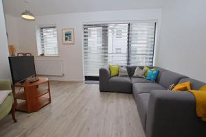 a living room with a gray couch and a television at Armada Close - 3 Story Home Close to Tunnels Beach in Ilfracombe