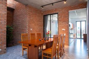 a dining room with a wooden table and a brick wall at CRIN HOUSE Đồng Châu in Lạc Thành