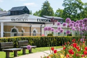 a park with a bench and flowers in front of a building at Europa Royale Druskininkai in Druskininkai