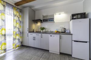 a kitchen with white cabinets and a refrigerator at FRAJDA Domki - Apartamenty 6-osobowe - salon i dwie sypialnie oraz Studia 4-osobowe - pokój z aneksem kuchennym in Rewal