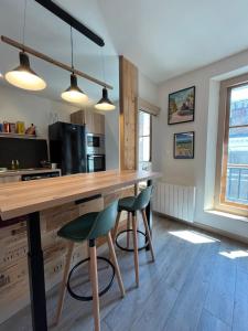 a kitchen with a wooden counter and two stools at Côté Médicis - Cosy appartement au coeur de Blois in Blois