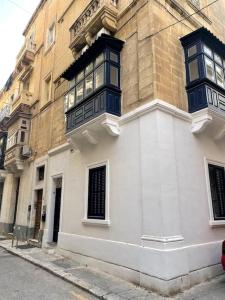 un bâtiment avec des fenêtres bleues sur son côté dans l'établissement Floriana Cosy Corner, à Il-Furjana 10 autres photos