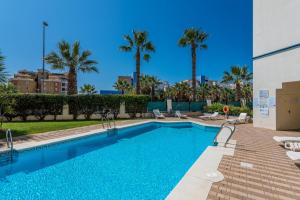 ein Swimmingpool mit Stühlen und Palmen in der Unterkunft Marina II by Ĥ - Marina Isla Canela PMHII27P65 in Punta del moral