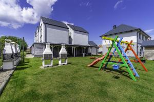 a yard with playground equipment in front of a house at FRAJDA Domki - Apartamenty 6-osobowe - salon i dwie sypialnie oraz Studia 4-osobowe - pokój z aneksem kuchennym in Rewal