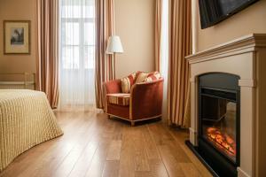 a living room with a fireplace and a chair at Europa Royale Druskininkai in Druskininkai