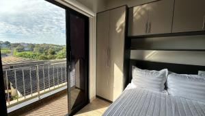 a bedroom with a bed and a balcony with a view at Lux Ville - Apartamento aconchegante no centro de Foz in Foz do Iguaçu