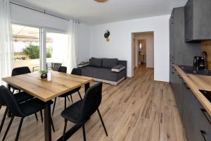a kitchen and living room with a wooden table and chairs at Luxury apartman Gino in Bibinje