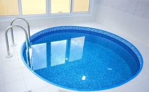 La salle de bains est pourvue d'une grande baignoire bleue. dans l'établissement Passion villa AL Jabal Alakhder باشن فيلا الجبل الأخضر, à Lālī Laynah