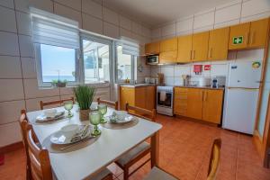 a kitchen with a white table and chairs and a table and a kitchen with at Mar Vista Home in Ponta Delgada