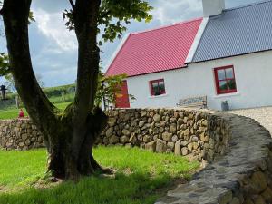 a tree in front of a stone wall next to a building at Farm Stay at THE GLEBE COTTAGE KILREA in Tamlaght