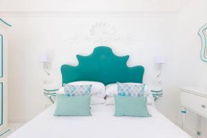a white bedroom with a white bed with blue pillows at Villa Nannina in Positano