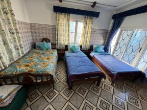 ein Schlafzimmer mit zwei Betten und zwei Fenstern in der Unterkunft Maison oudelaou in Oued Laou